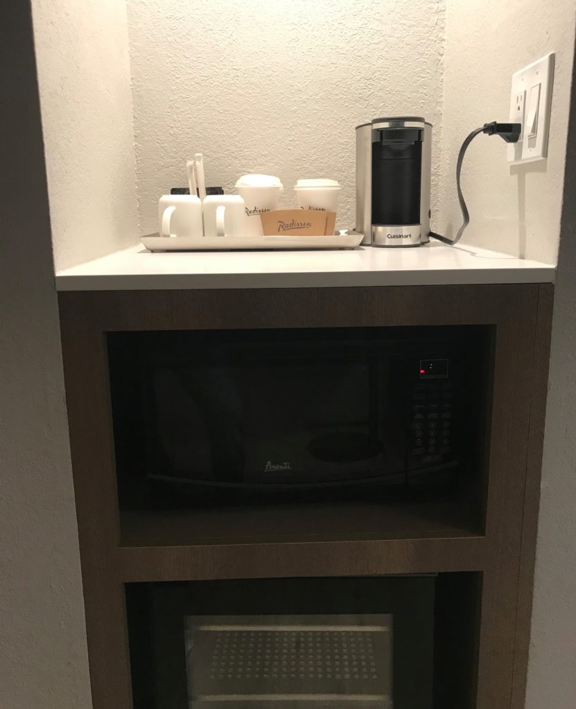 a microwave and coffee cups on a shelf