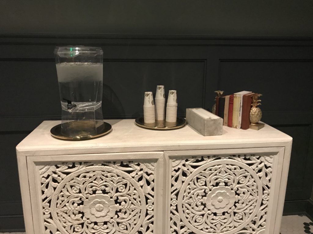 a white cabinet with a glass of water and books on it