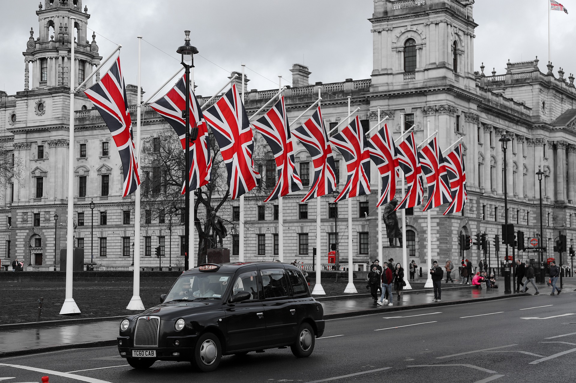 a black car on a street with flags in front of a building