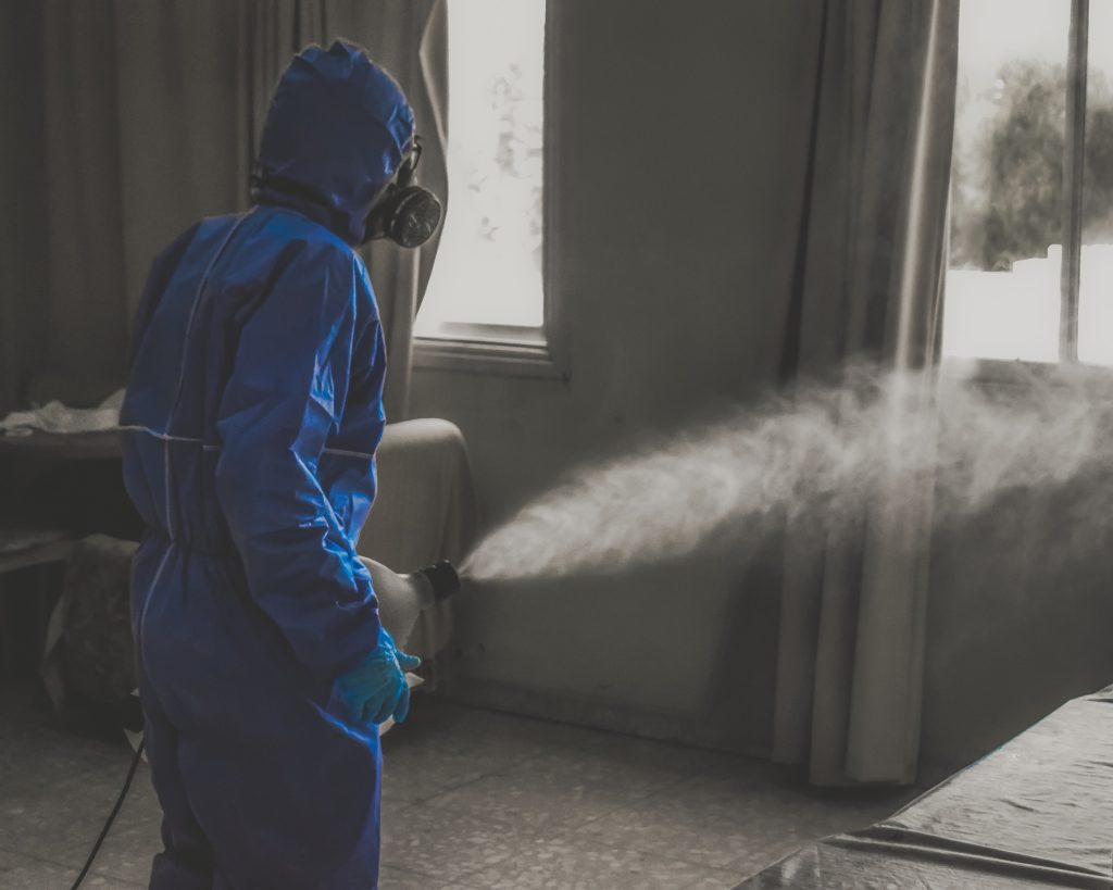 a person in a blue suit spraying a bed