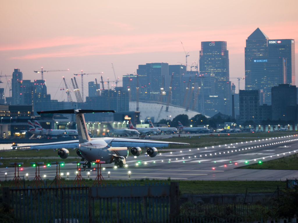 an airplane on a runway with a city in the background