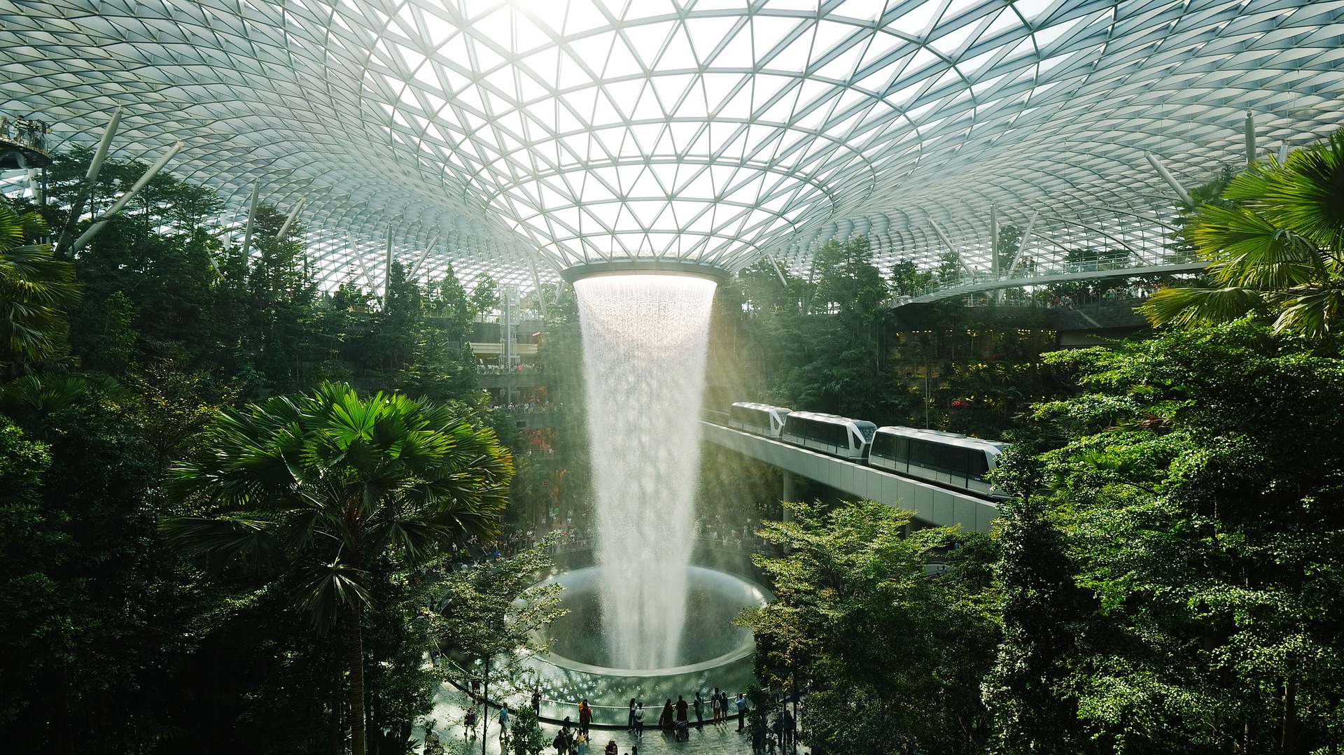 a large glass dome with a water fountain and people walking around