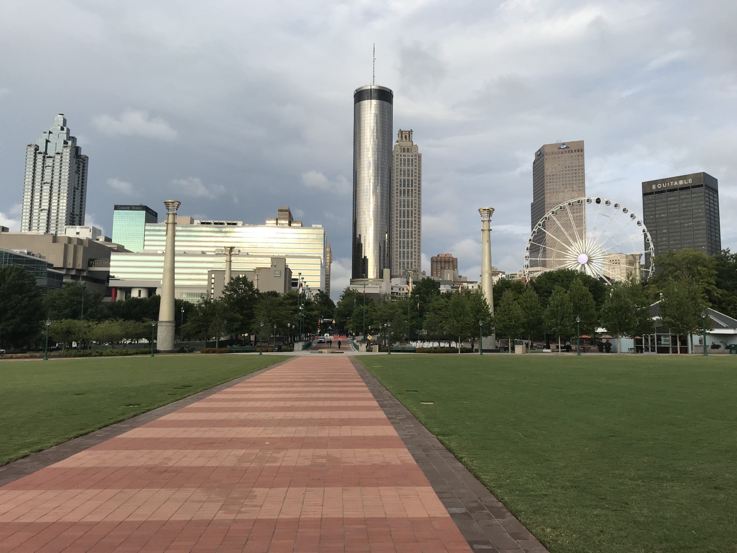 a park with a walkway and a ferris wheel in the background