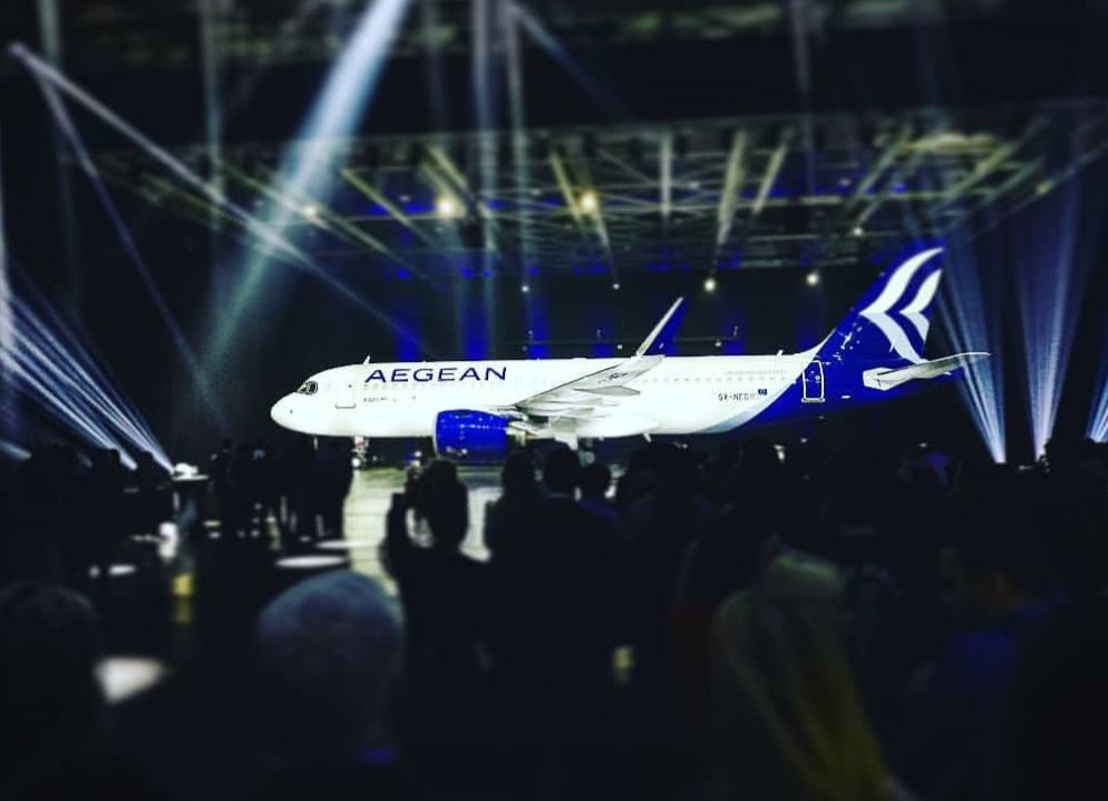 a large white and blue airplane in a large room with people