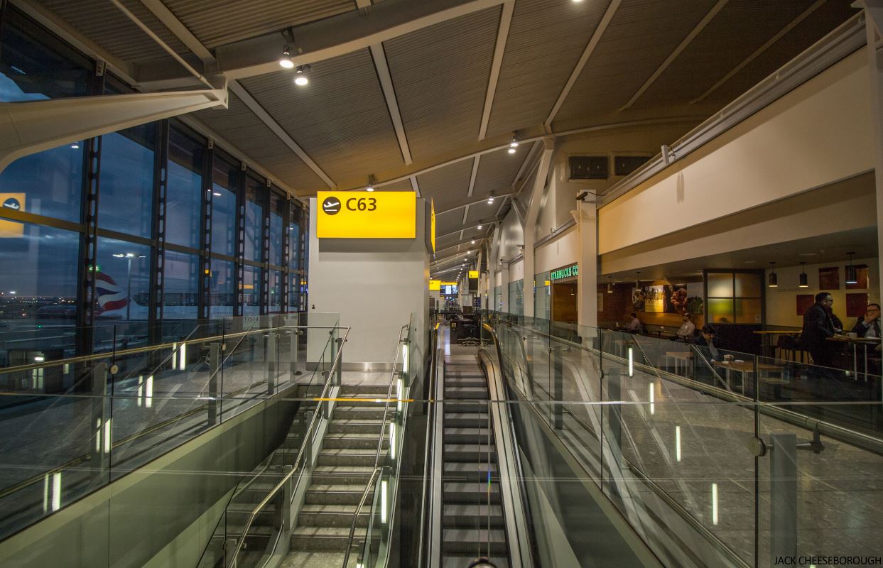 an airport with escalators and a yellow sign