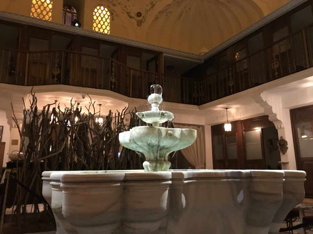 a fountain in a room with a balcony and a building
