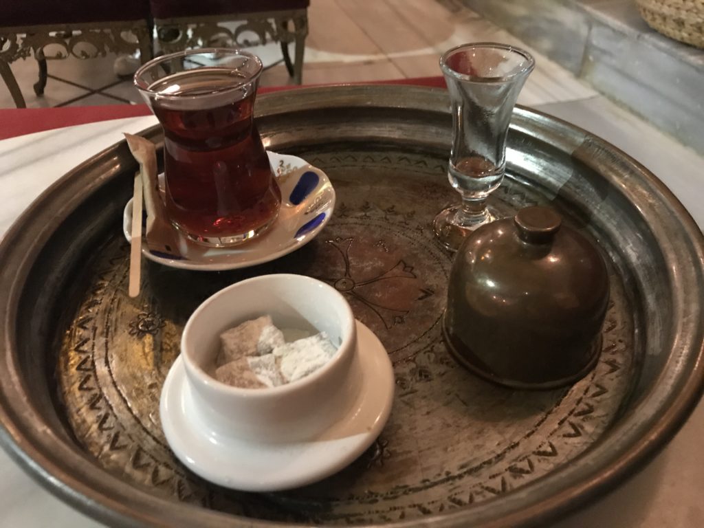 a tray with a glass of tea and a small glass of sugar