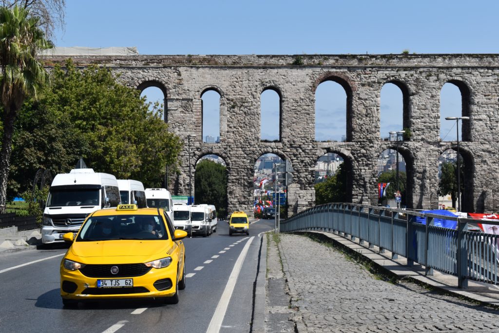 a yellow car on a road with a bridge over it