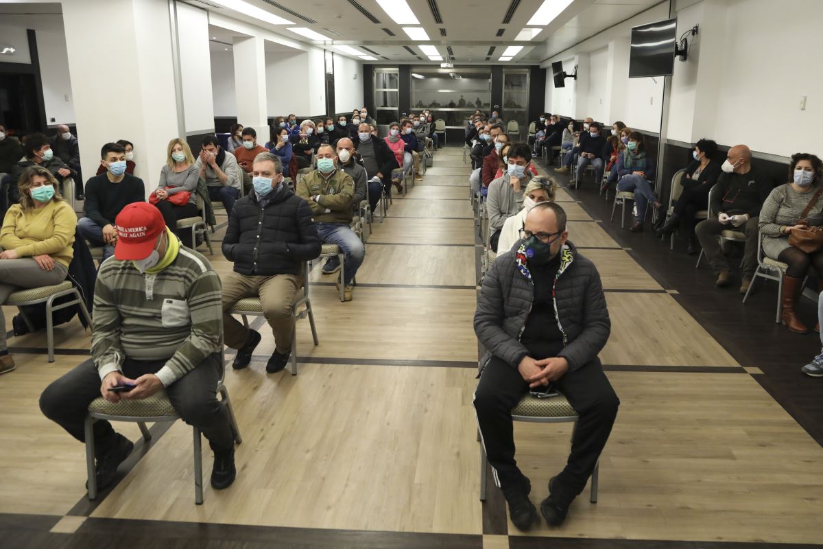 a group of people sitting in chairs wearing face masks