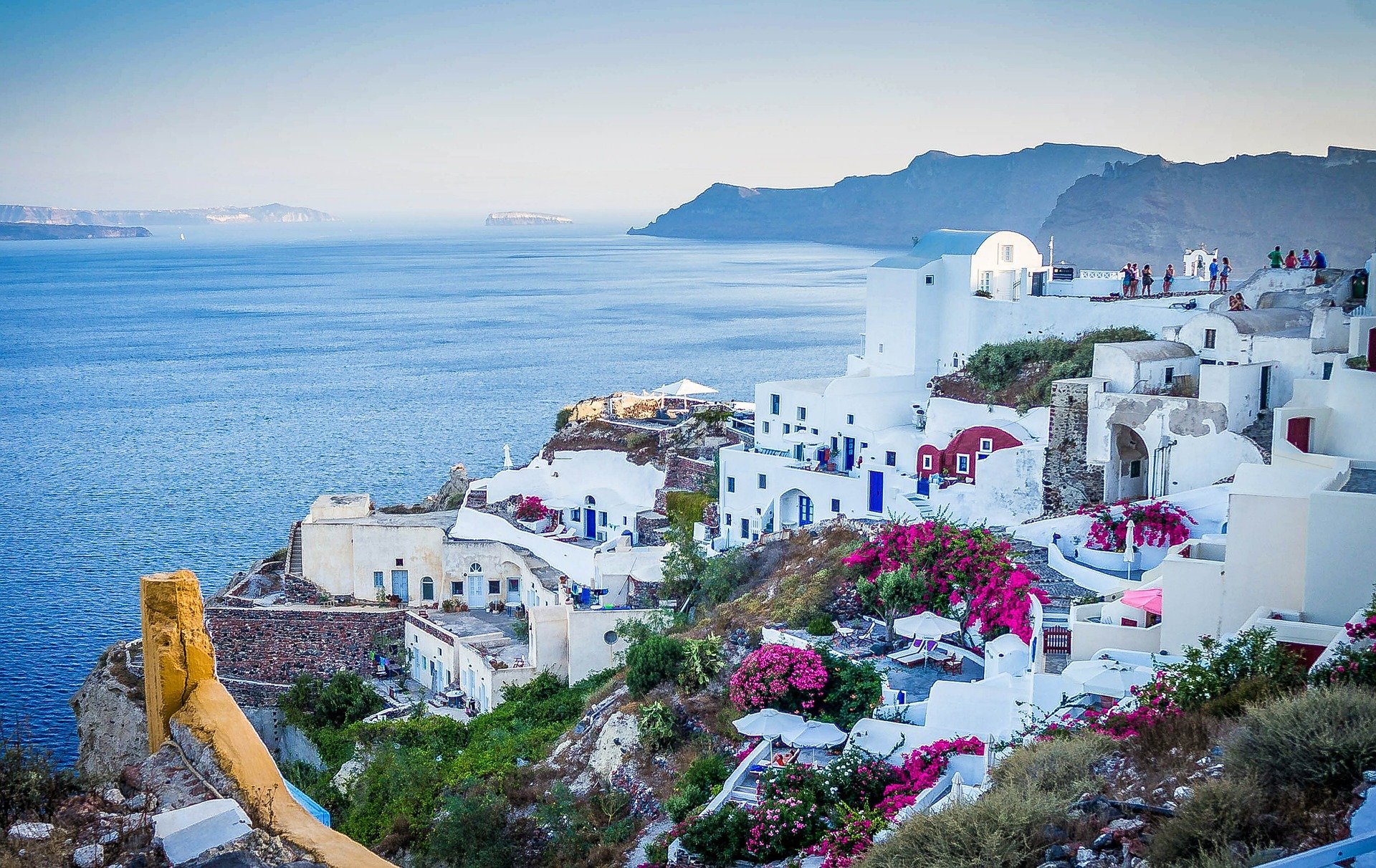 a white buildings on a hill next to a body of water