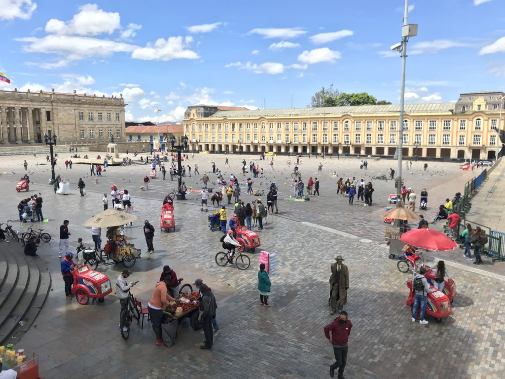 a large square with people and bicycles and umbrellas