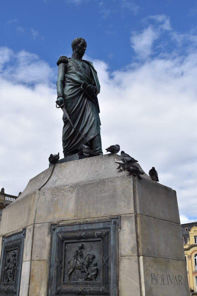 a statue of a man with a sword and pigeons on top of a concrete block