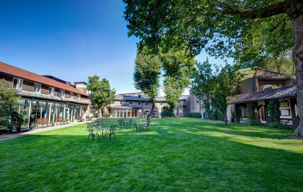 a lawn with chairs and tables in front of buildings