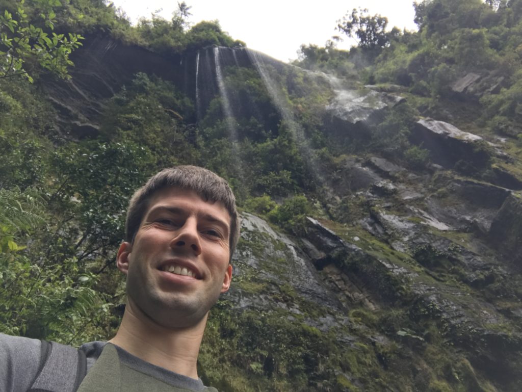 a man taking a selfie in front of a waterfall