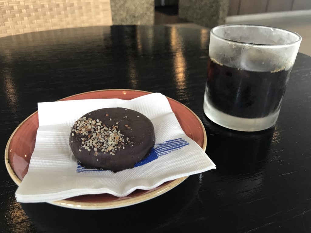 a donut on a plate next to a glass of liquid