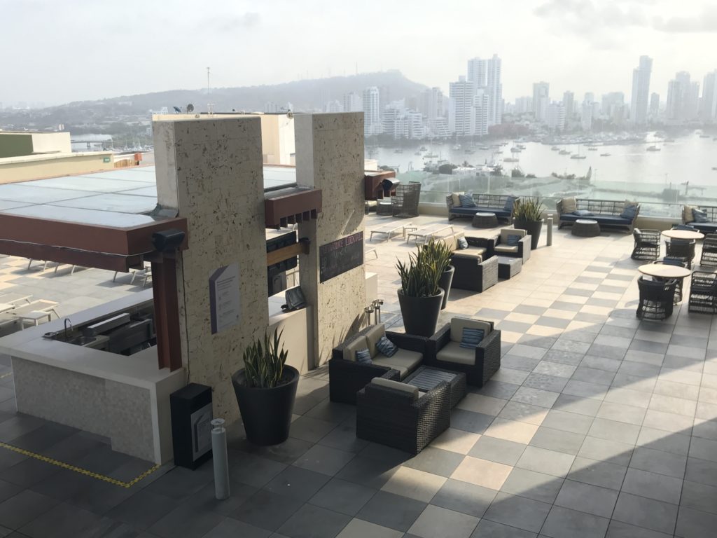 a rooftop patio with chairs and a city view