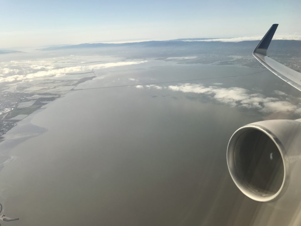 an airplane wing with a view of land and clouds
