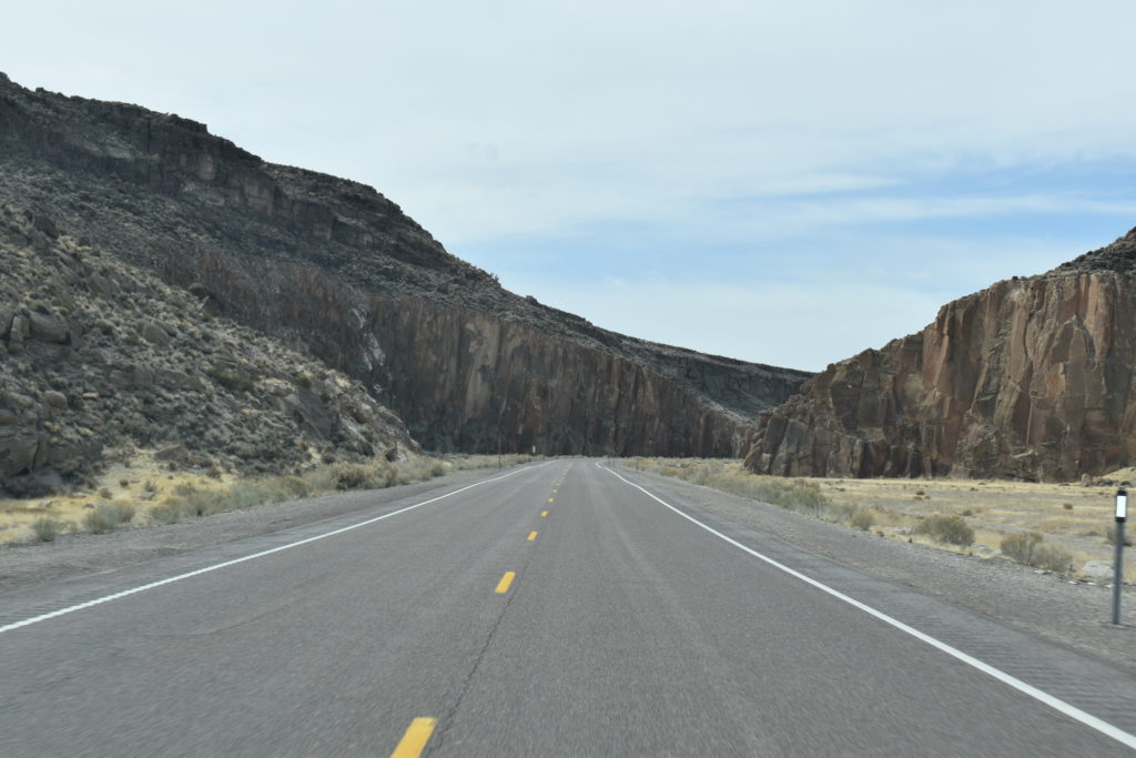 a road with a rocky cliff in the background
