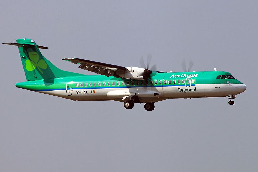 a green and white airplane in the sky