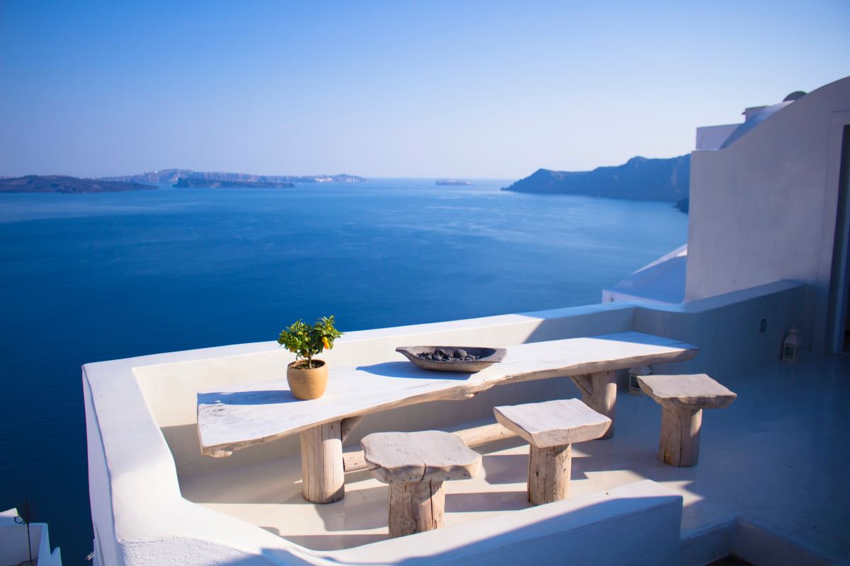 a table and benches overlooking the ocean with Santorini in the background