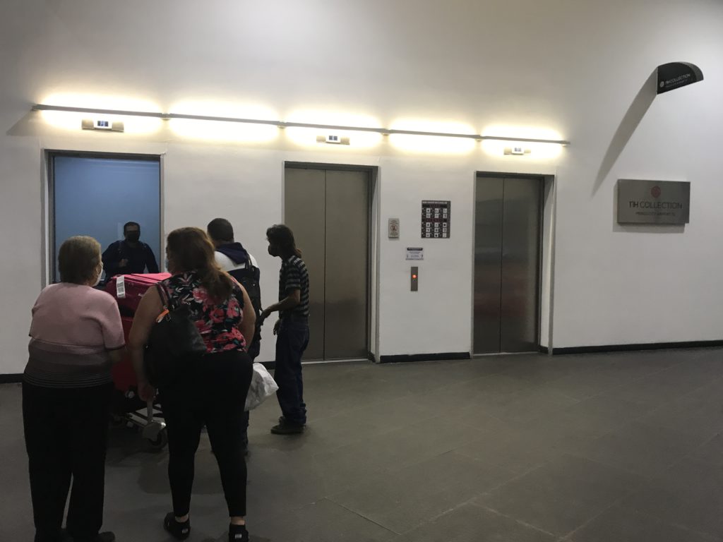 a group of people standing in a hallway with elevator doors