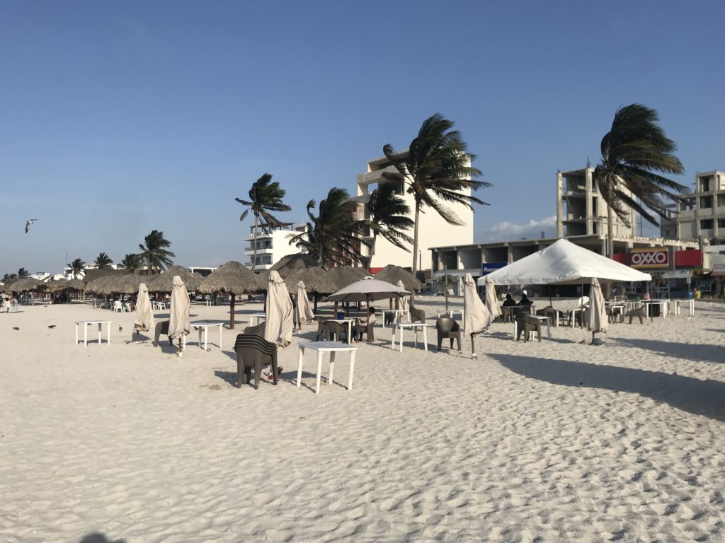 a beach with umbrellas and tables and chairs