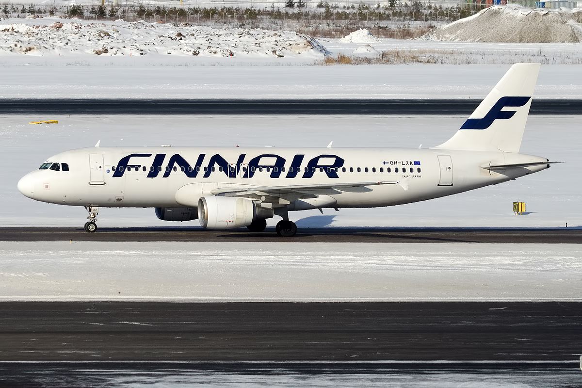 a white airplane on a runway with snow