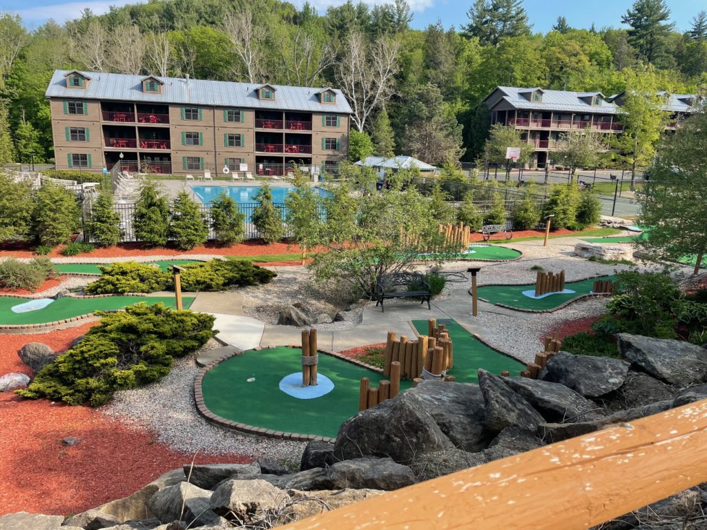 a mini golf course with a pool in the background