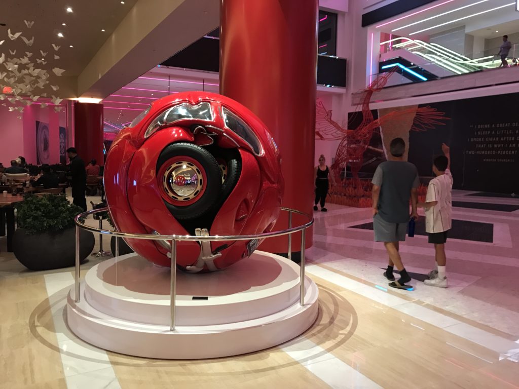 a red object on a stand in a room with people