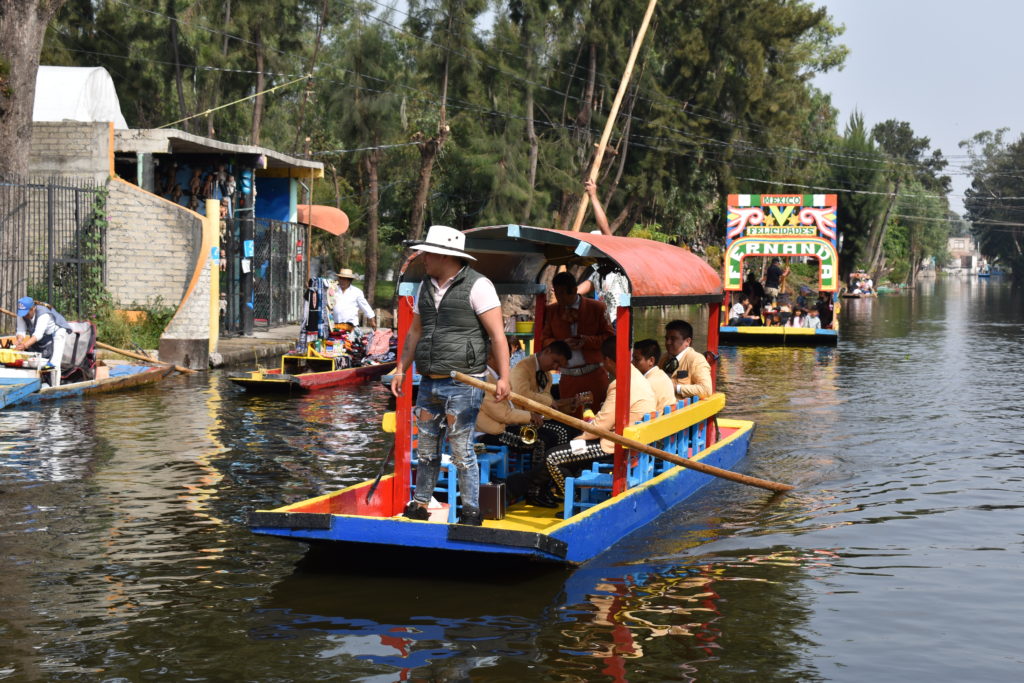 a group of people in a boat with Xochimilco in the background