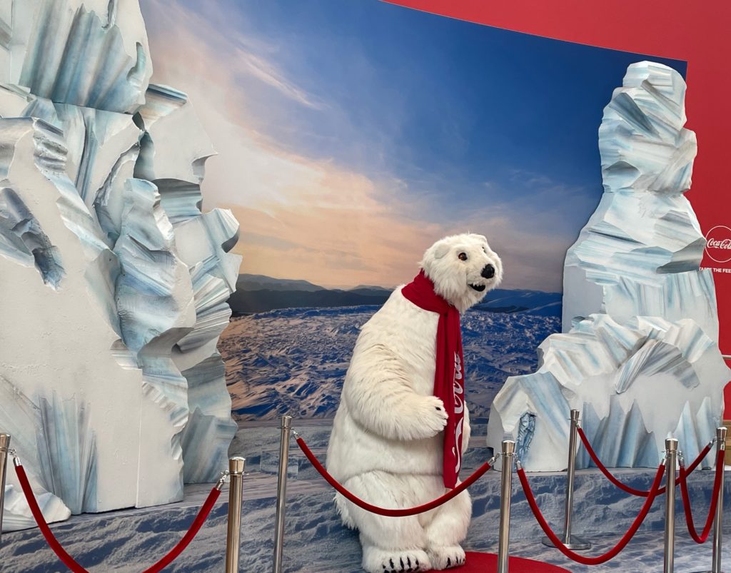 a polar bear wearing a scarf and standing on a red carpet