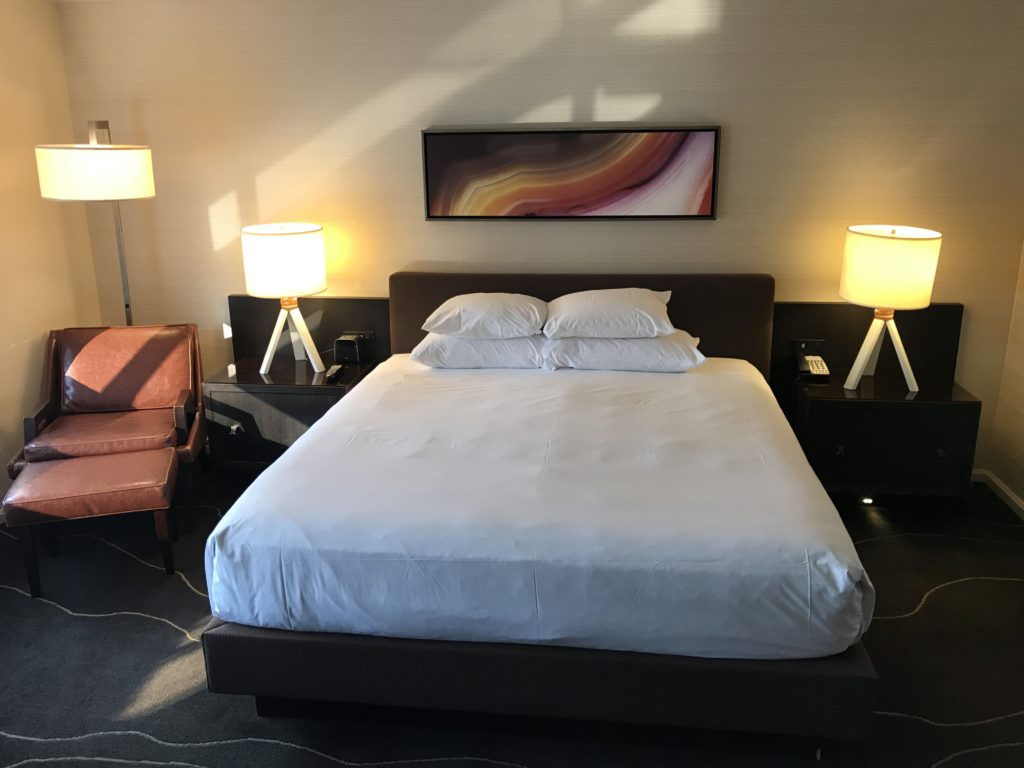 a bed with white sheets and lamps in a room