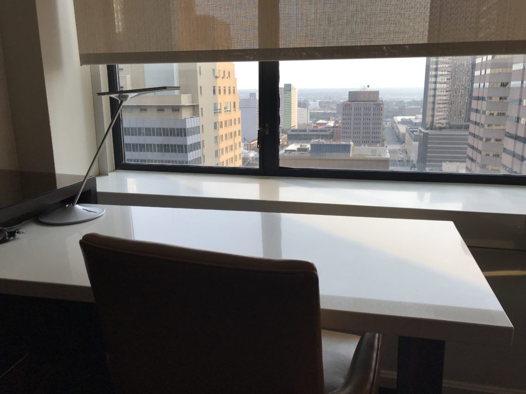 a table with a lamp and a chair in front of a window