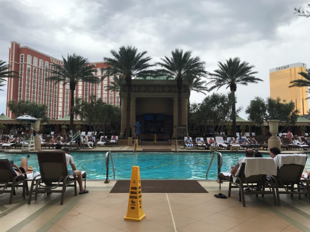 a pool with people sitting in chairs and palm trees
