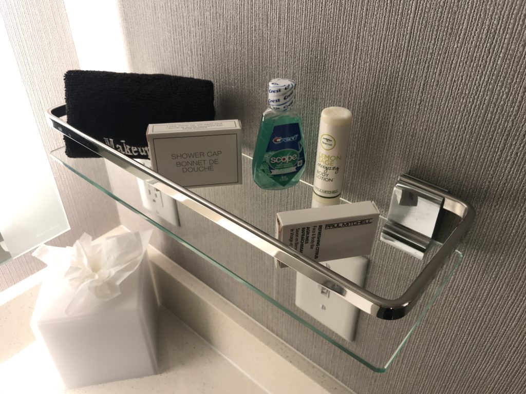 a glass shelf with a group of bathroom items on it