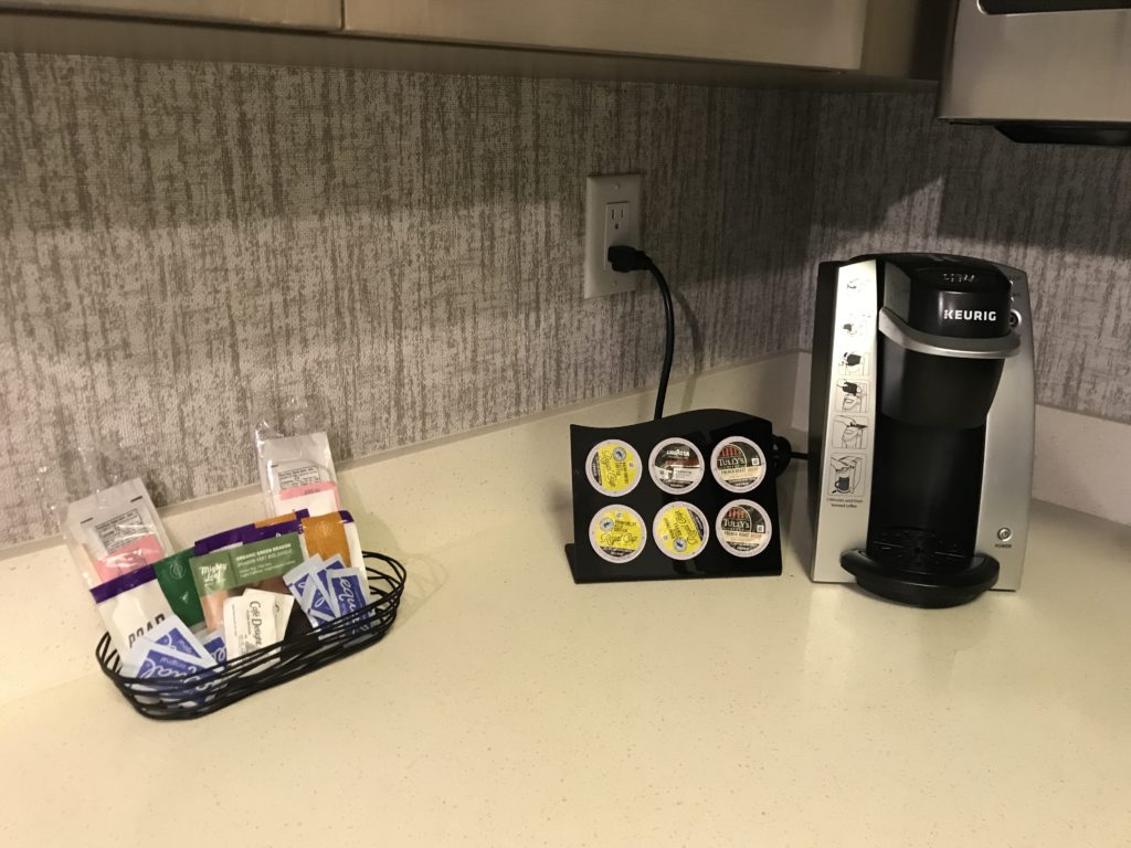 a coffee maker and a basket of condiments