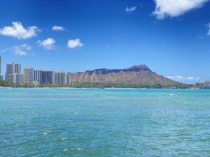 a body of water with buildings in the background with Diamond Head in the background