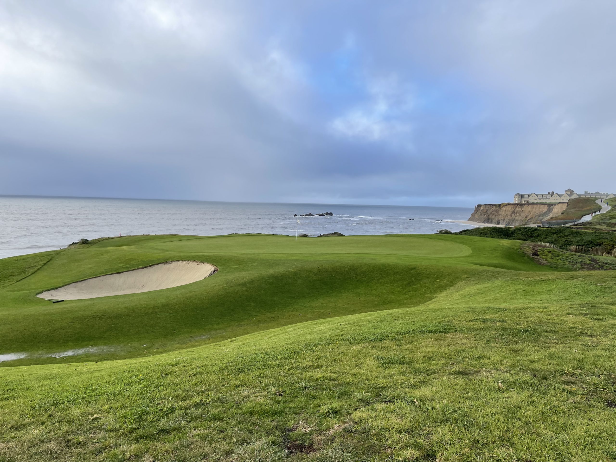 a golf course with a sand bunker and a body of water