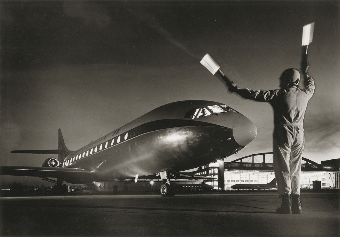 a man holding a flashlight next to an airplane