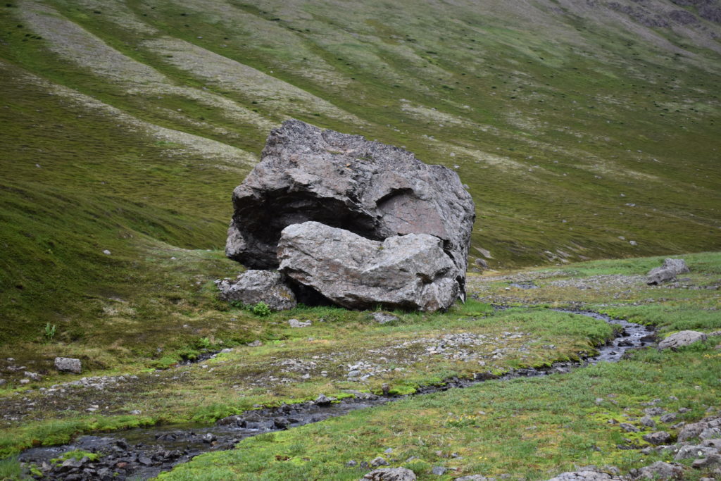 a large rock on a grassy hill