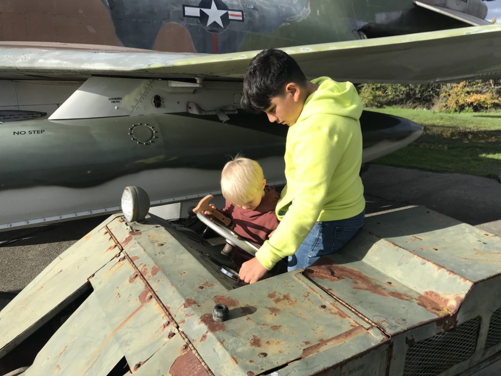 two boys playing in a military vehicle