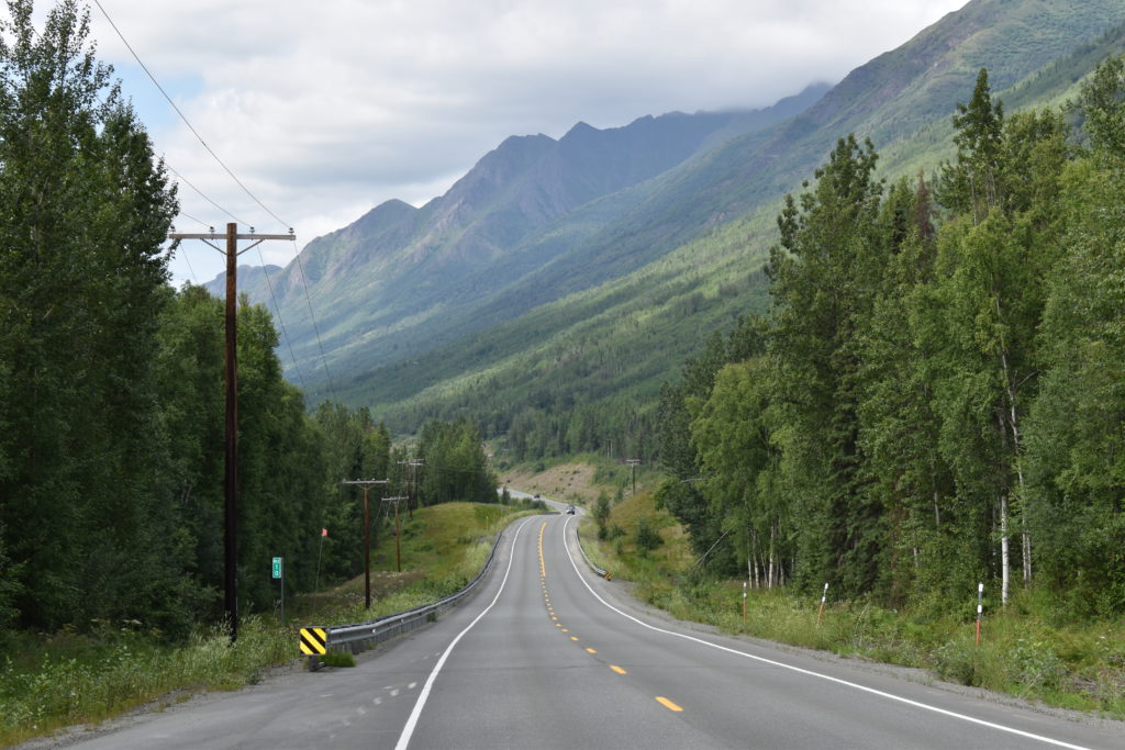 a road with trees and mountains in the background with Alberta Highway 93 in the background