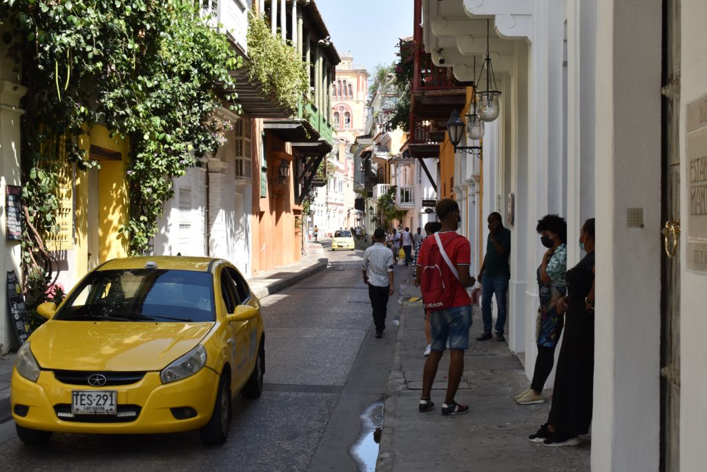 a group of people standing on a street with a yellow car