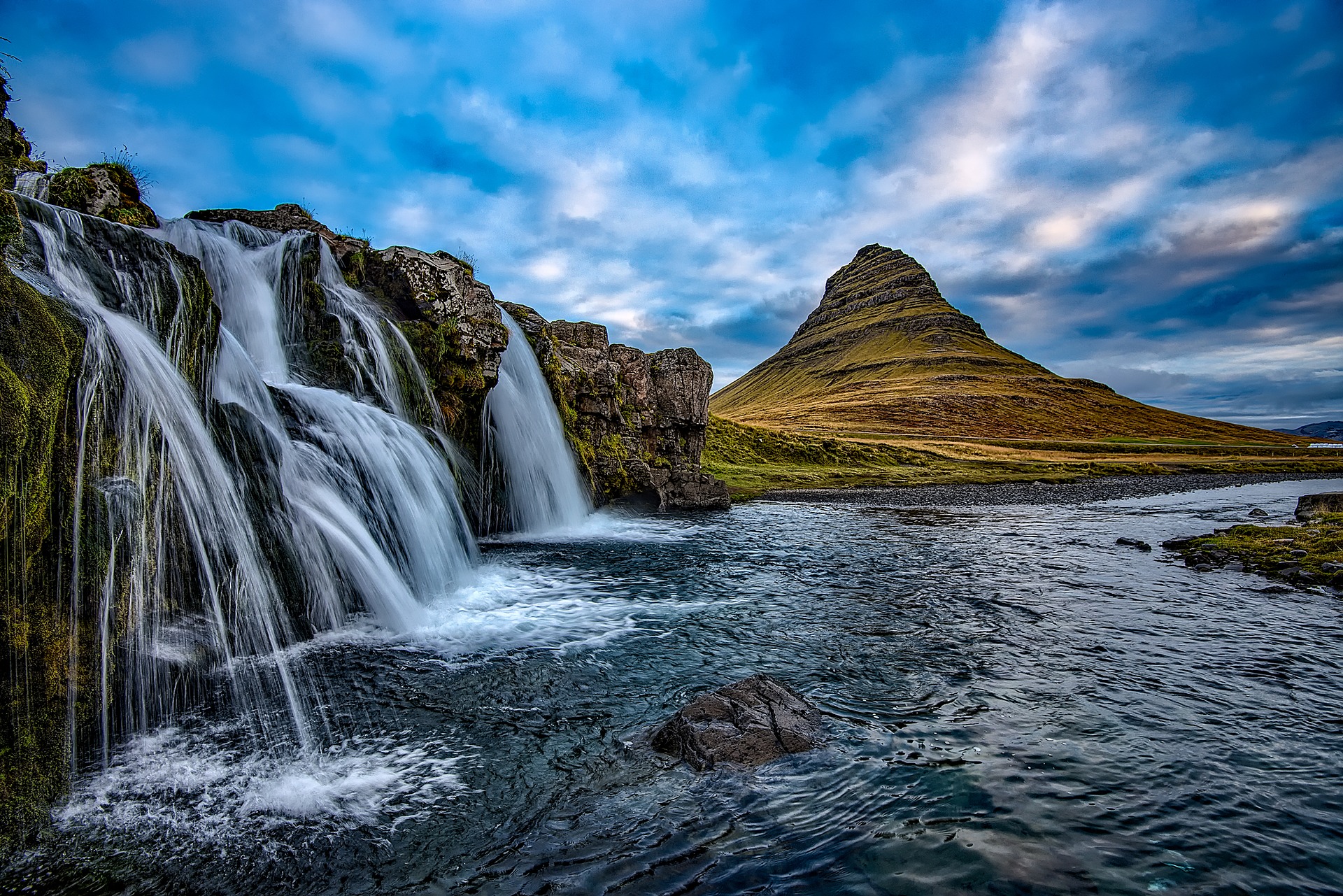 a waterfall next to a mountain