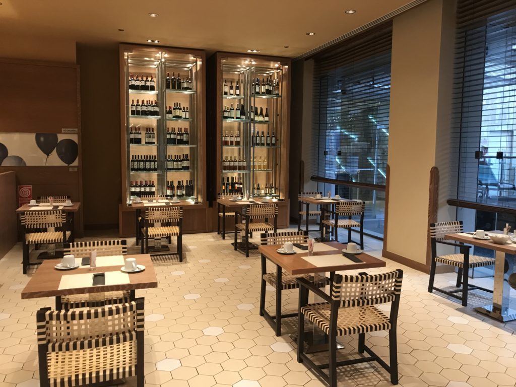 a room with tables and chairs and shelves of wine bottles