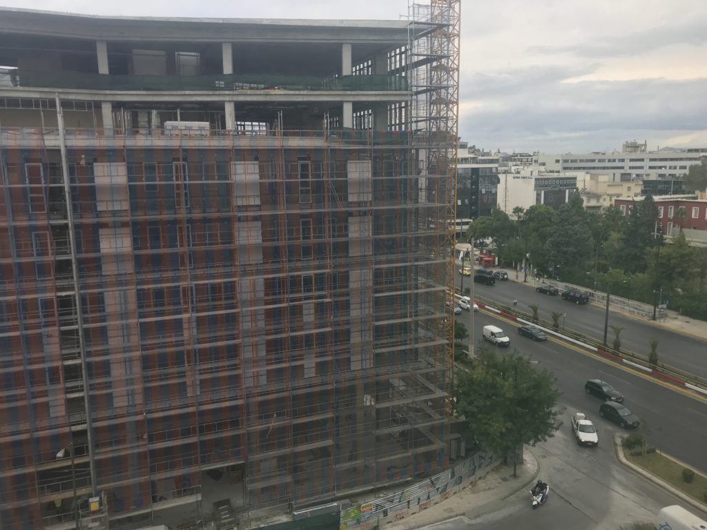 a building under construction with cars on the street