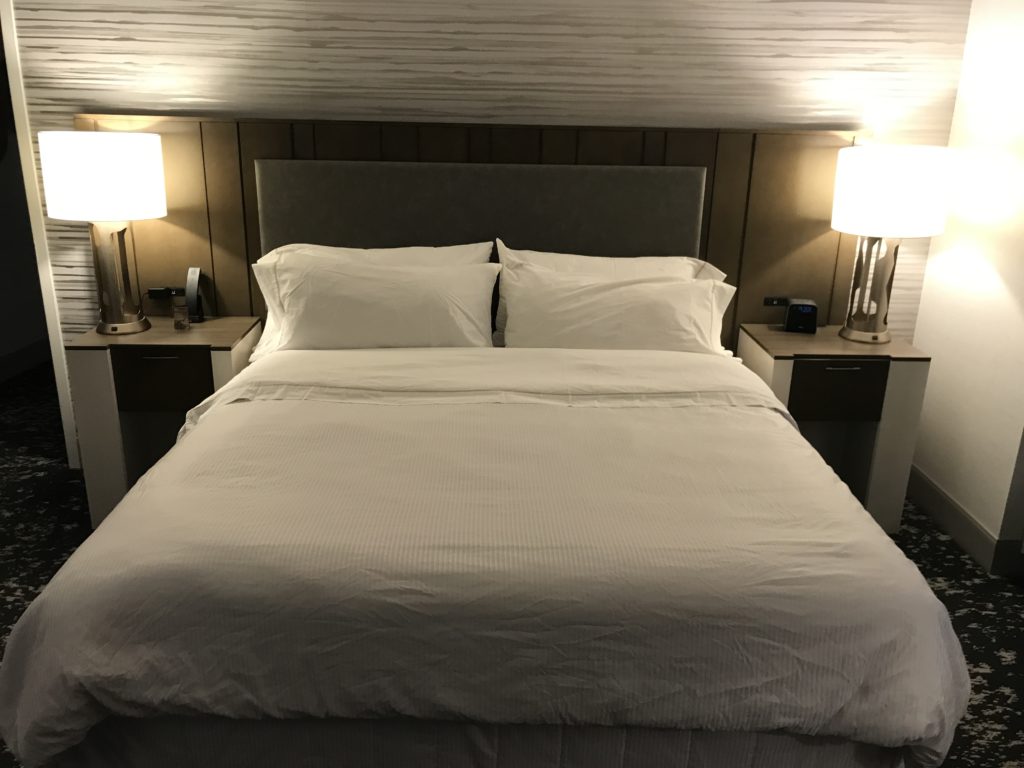 a bed with white sheets and lamps