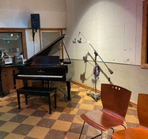 a piano in a room with chairs and microphones