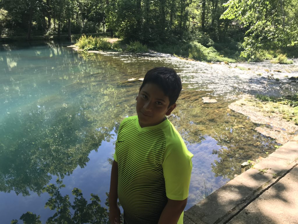 a boy standing in front of a body of water