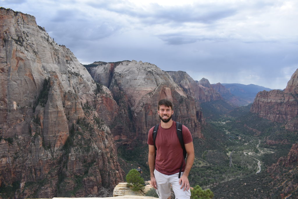 a man standing on a cliff with a mountain in the background